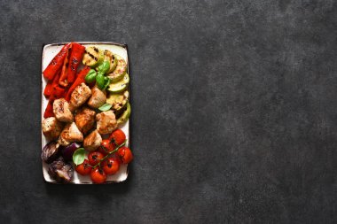 Izgara et ve sebzeler: domates, soğan, kabak, beton kaplama bir tabakta biber. Piknik. Barbekü menüsü.