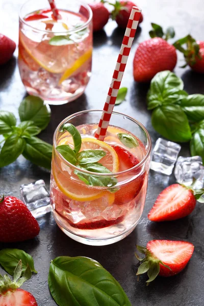 Summer drink. Cold lemonade with strawberries and basil on a concrete background.