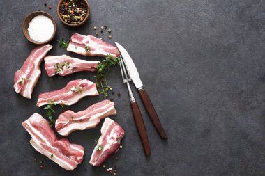 Siyah taş zemin üzerinde kekik olan çiğ domuz pirzolası. Yukarıdan bak. Taze et..