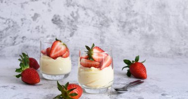 Beton arka planda kremalı ve çilekli tatlı. Panna cotta.