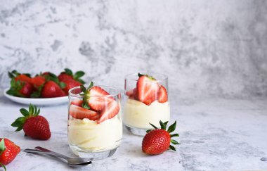Beton arka planda kremalı ve çilekli tatlı. Panna cotta.
