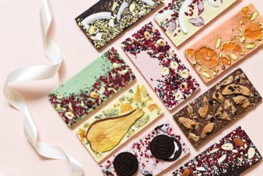 Farklı dolgulu el yapımı çikolata: kurabiyeler, lavanta, gül, portakal, armut, hindistan cevizi, ceviz, şekerli meyve, narin bej arkaplanda peynir.