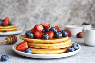 Mutfak masasında kahvaltıda çilekli ve yabanmersinli ev yapımı krepler..