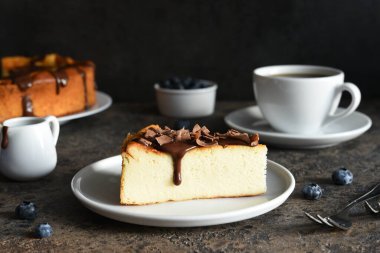 Cheesecake New York 'ta. Çikolata soslu cheesecake ve koyu beton arka planda bir fincan kahve..