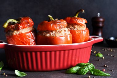 Doldurulmuş biber. Koyu beton bir arka planda pilav, et ve fesleğenle pişirilmiş biber..