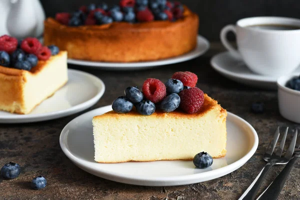 Cheesecake New York 'ta. Ahududu ve yaban mersinli cheesecake, koyu arkaplanda bir fincan çay..