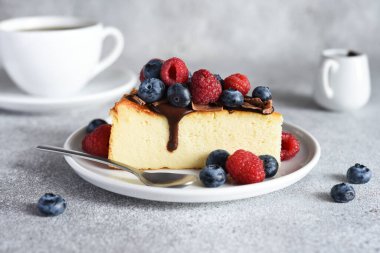 Çikolata soslu bir dilim cheesecake, böğürtlen ve bir fincan kahve....