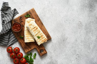 Tahta bir tahtada et ve sebzelerle doldurulmuş Shawarma beton bir zemine karşı. Yukarıdan görüntüle.