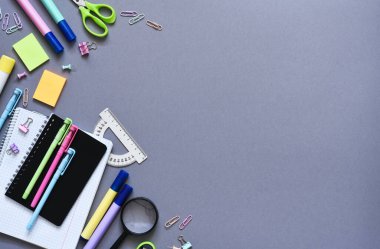 Okula dönelim. Okul malzemeleri: Gri arka planda defter, kalem, kalem. Yukarıdan bak. Ofis araçları.
