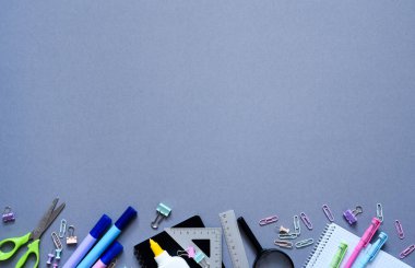 Okula dönelim. Okul malzemeleri: Gri arka planda defter, kalem, kalem. Yukarıdan bak. Ofis araçları.