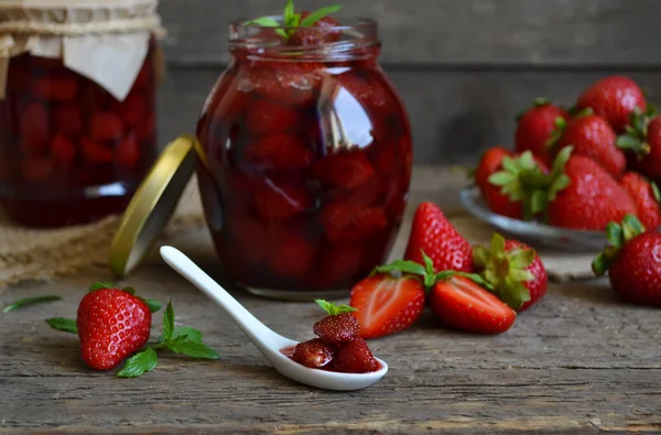 Strawberry jam in jar on a wooden background
