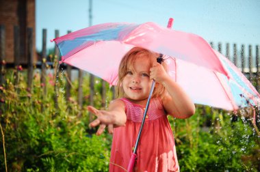 Küçük kız şemsiye yağmur altında tutan