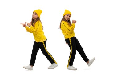 Sarı eşofman giyen, el kol hareketleriyle el kol hareketi yapan ve beyaz bir arka plana sevinç yansıtan genç bir kızın tam boy portresi. Mutlu gençlik kavramı