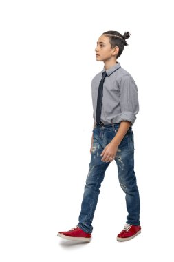 Modası geçmiş bir saç kesimi olan, mavi gömlekli, kravatlı ve beyaz arka planda kot pantolon giyen bir çocuğun fotoğrafı.