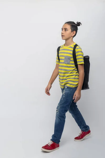 스튜디오는 노란색과 셔츠를 배경에 청바지를 포니테일이 배낭을 소년의 사진을 찍었다 — 스톡 사진