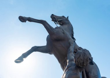 St. Petersburg 'daki Nevsky Prospect' te, Anichkov köprüsünde atı ehlileştiren ünlü bronz heykel atleti mavi gökyüzüne karşı.