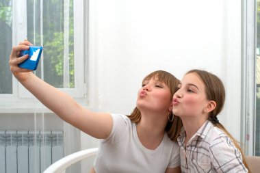 Evde dinlenen genç kızlar boş zamanlarını birlikte geçirirler, akıllı telefon tutarlar, kız arkadaşlarıyla fotoğraf çektirirler, sosyal ağlar için poz veren videolar çekerler.