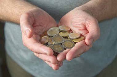 Avuçlarında avuçlarının içinde bir avuç avro sikkesi tutan iki adam..