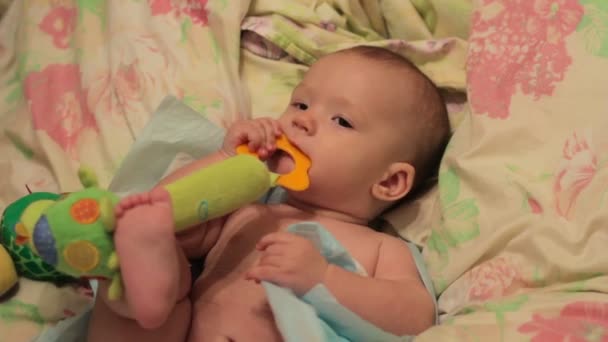 Baby spelen met speelgoed op bed — Stockvideo