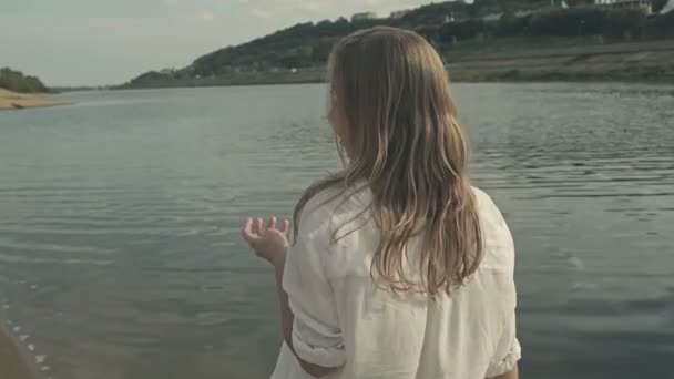 Belle fille parler sur l'eau et se tourne vers la caméra — Video