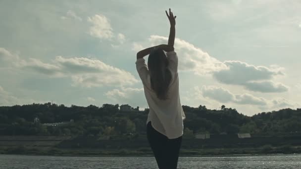 dívka stojí u řeky a vesele zvedá ruce