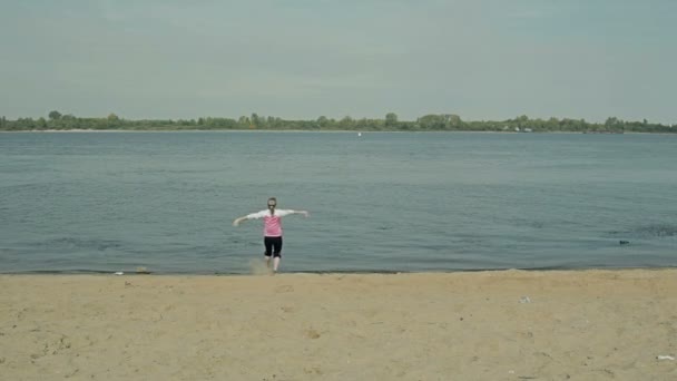 Ragazza che corre gioiosamente vicino all'acqua sulla spiaggia sporca — Video Stock