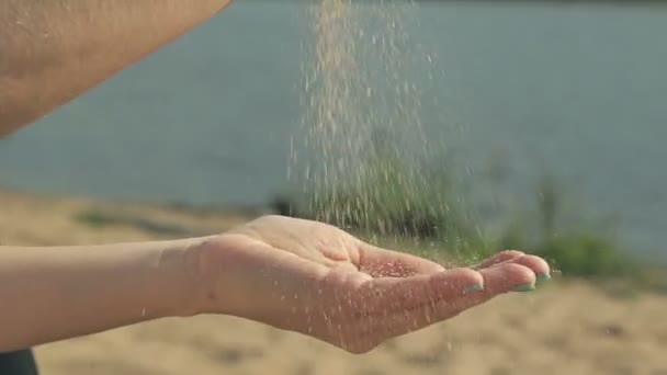 Девушка льет песок в руки — стоковое видео