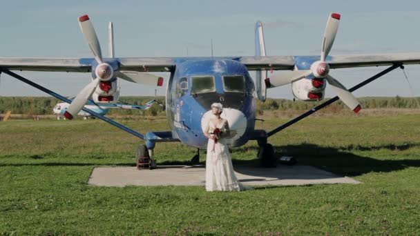 Sposa in abito da sposa si trova vicino a un vecchio aereo — Video Stock