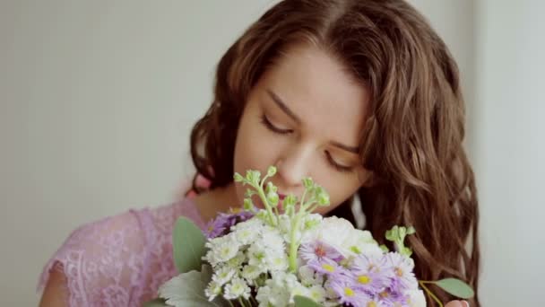 Piękna dziewczyna w różowej sukience wdycha zapach bukiet kwiatów. Szczelnie-do góry — Wideo stockowe