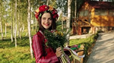 kafasını ve kameraya bakarak ve gülümseyerek onu elinde bir buket çelenk ile güzel esmer