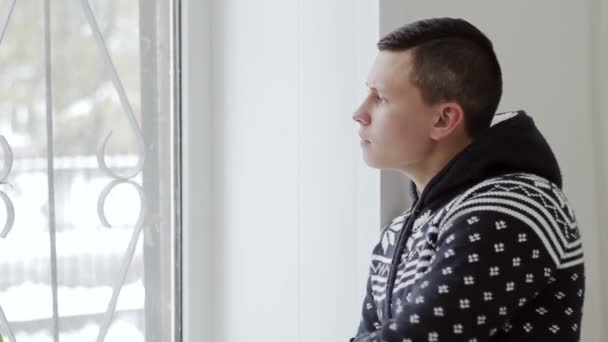 Чоловік у теплому светрі кашляє стоячи біля вікна — стокове відео