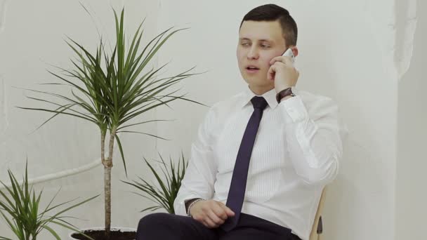 Empresario hablando por teléfono sentado en una silla de madera — Vídeos de Stock