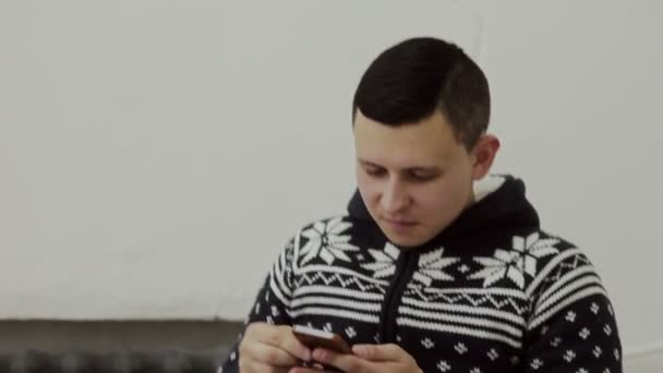 Chico en un suéter fotos de ti mismo en el teléfono — Vídeos de Stock