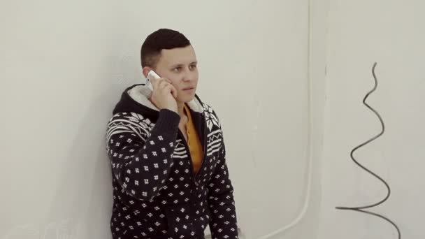 Handsome young man in a sweater talking on the phone — Stock Video