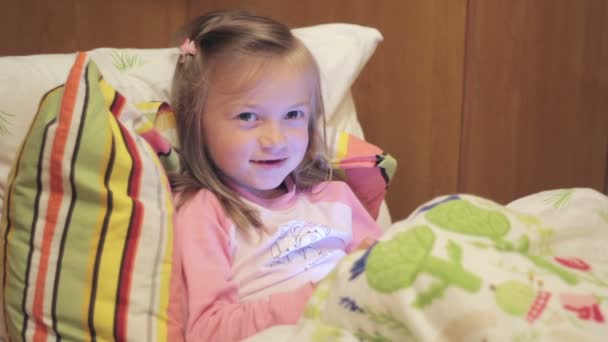 Kis lány az ágyon, énekel egy dalt a tabletta — Stock videók
