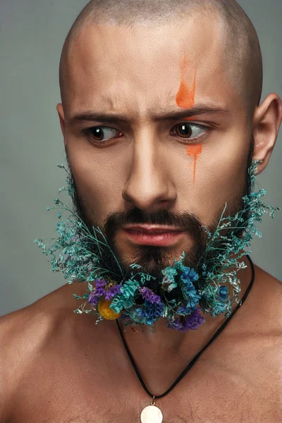 Людина з креативним макіяжем і квітами в його бороді — стокове фото