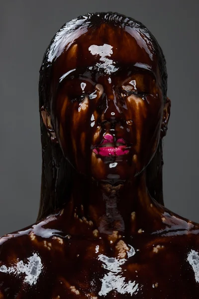 Όμορφη νεαρή γυναίκα μελαχρινή με σοκολάτα που ρέει στο πρόσωπό — Φωτογραφία Αρχείου