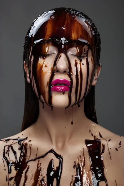 Bela jovem morena mulher com chocolate fluindo no rosto — Fotografia de Stock