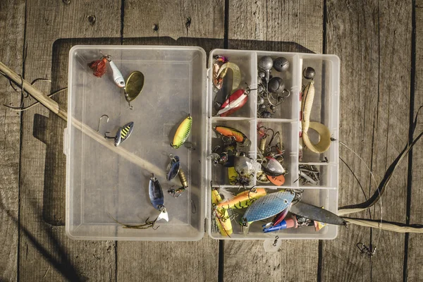 Señuelos de pesca y accesorios en la caja sobre fondo de madera — Foto de Stock