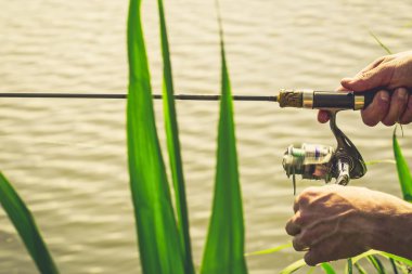 Nehir kıyısında elinde olta olan bir balıkçı.