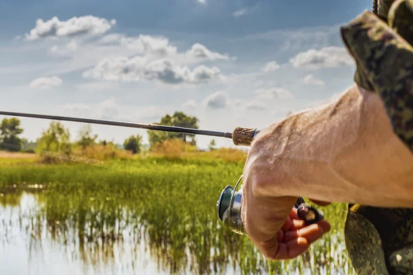 Pescador con caña de pescar en la orilla del río — Foto de Stock