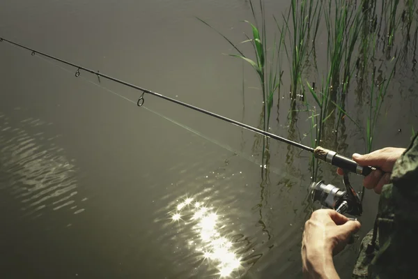 Pescador con caña de pescar en la orilla del río — Foto de Stock