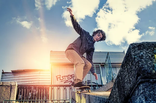 Skateboarder doen een skateboard springen truc bij zonsopgang city — Stockfoto