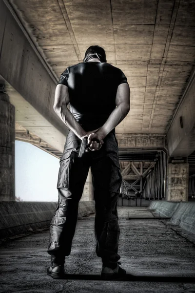 Man in black uniform and mask standing with gun — Stock Photo, Image