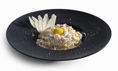 Makarna carbonara parmesan ve izole sarısı dilimleri ile dekore edilmiştir.