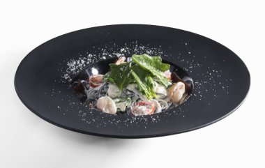 Siyah mat plaka üzerinde beyaz izole karides ile Tagliatelle