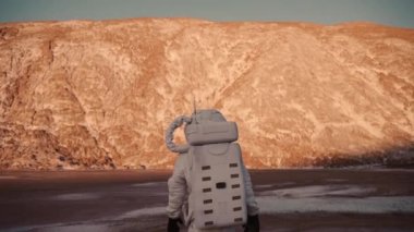 Astronot tepeye doğru yürüyor. Astronot bilinmeyen bir gezegende yürüyor.