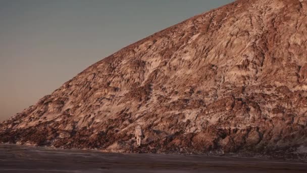 Um astronauta ao pé da colina dá os primeiros passos para escalá-la — Vídeo de Stock