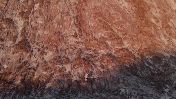 El astronauta está de pie sobre una roca. fotografía aérea — Vídeo de stock