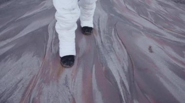 Astronot bilinmeyen bir gezegenin katı yüzeyinde yavaşça ve dikkatlice yürür.